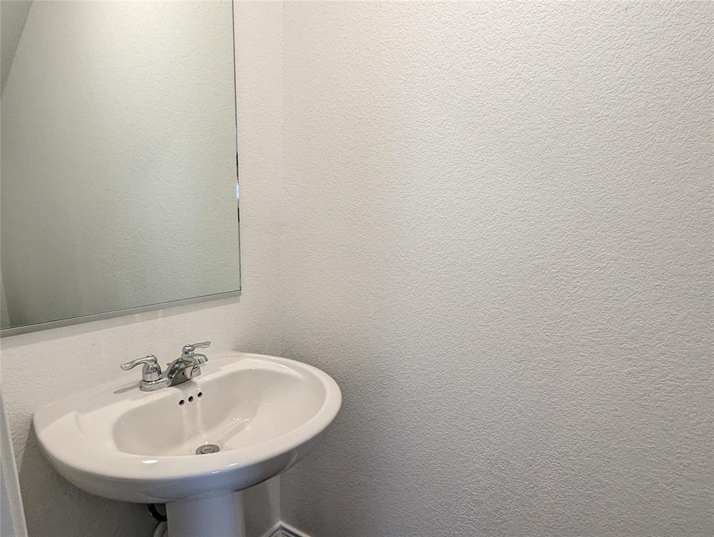 152 Avre Loop Kyle, TX 78640 - Photo 6 of 24 A pristine pedestal sink paired with a simple wall-mounted mirror offers functionality in this compact space.