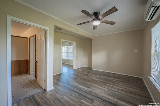 an empty room with wooden floor fan and windows