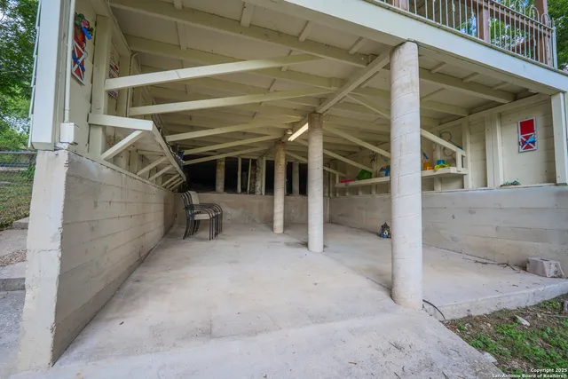 a view of a backyard with large trees and wooden fence