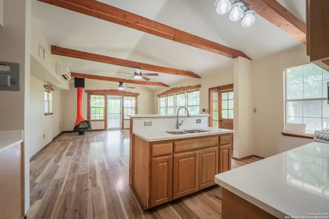 a large white kitchen with wooden floor and a sink