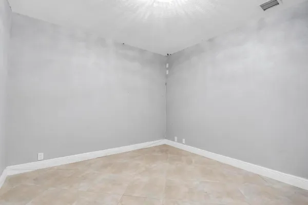 a view of an empty room with a window and kitchen area