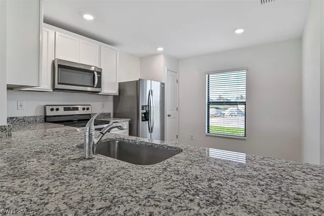 a kitchen with stainless steel appliances granite countertop a sink a stove a microwave a refrigerator and a stove