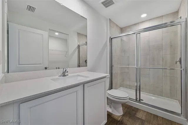 a bathroom with a shower sink vanity mirror and toilet