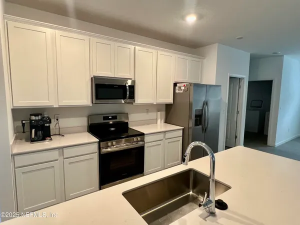 a kitchen with a refrigerator stove top oven and sink