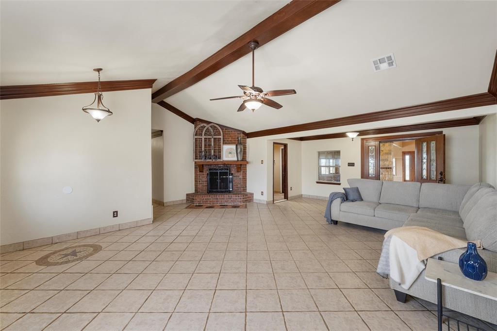3433 West Tours Road West, TX 76691 - Photo 7 of 40 Living area featuring ceiling fan, a brick fireplace, light tile patterned flooring, and ornamental molding