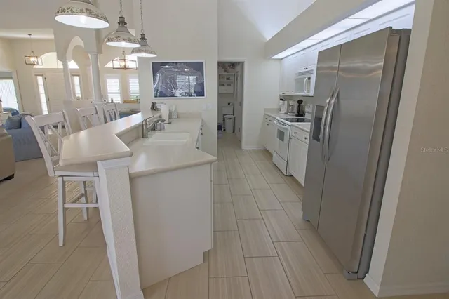a kitchen with stainless steel appliances kitchen island granite countertop a table chairs sink and cabinets