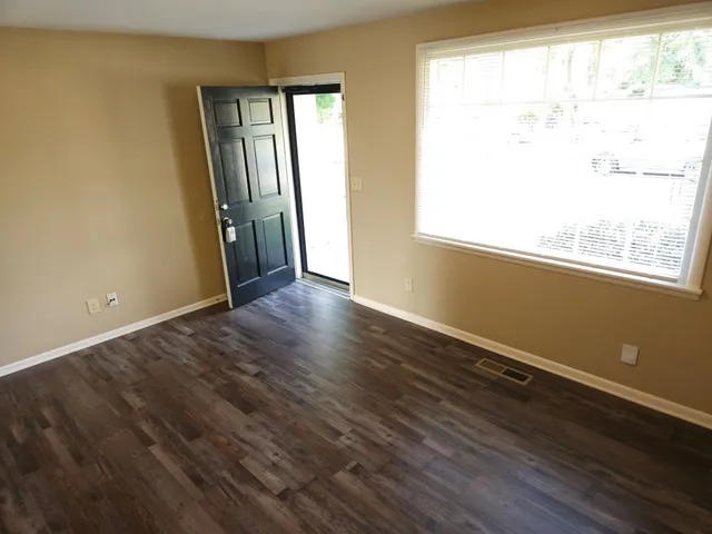 a view of an empty room with wooden floor and a window