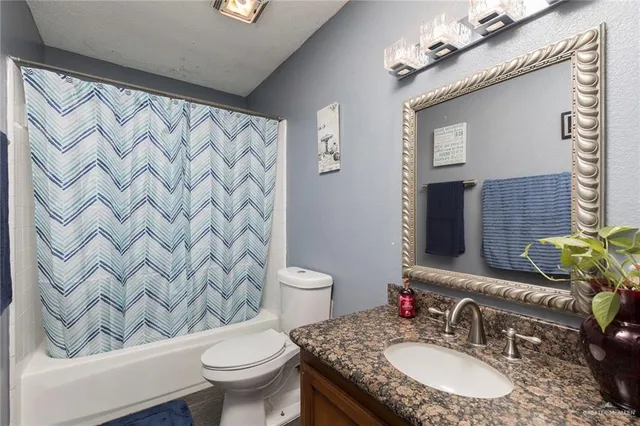 a bathroom with a granite countertop sink a toilet and a mirror