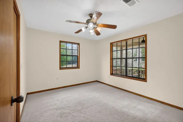 an empty room with windows and fan