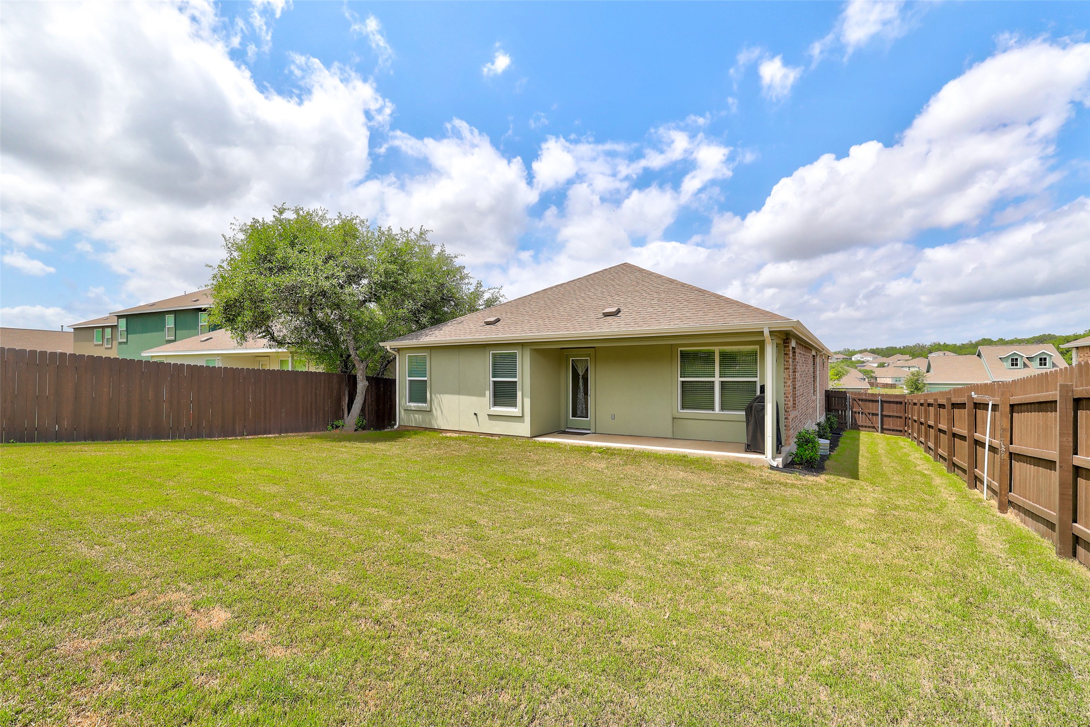 2333 Four Waters Loop Georgetown, TX 78628 - Photo 33 of 35 Spacious backyard featuring a manicured lawn, established tree, and a wood privacy fence