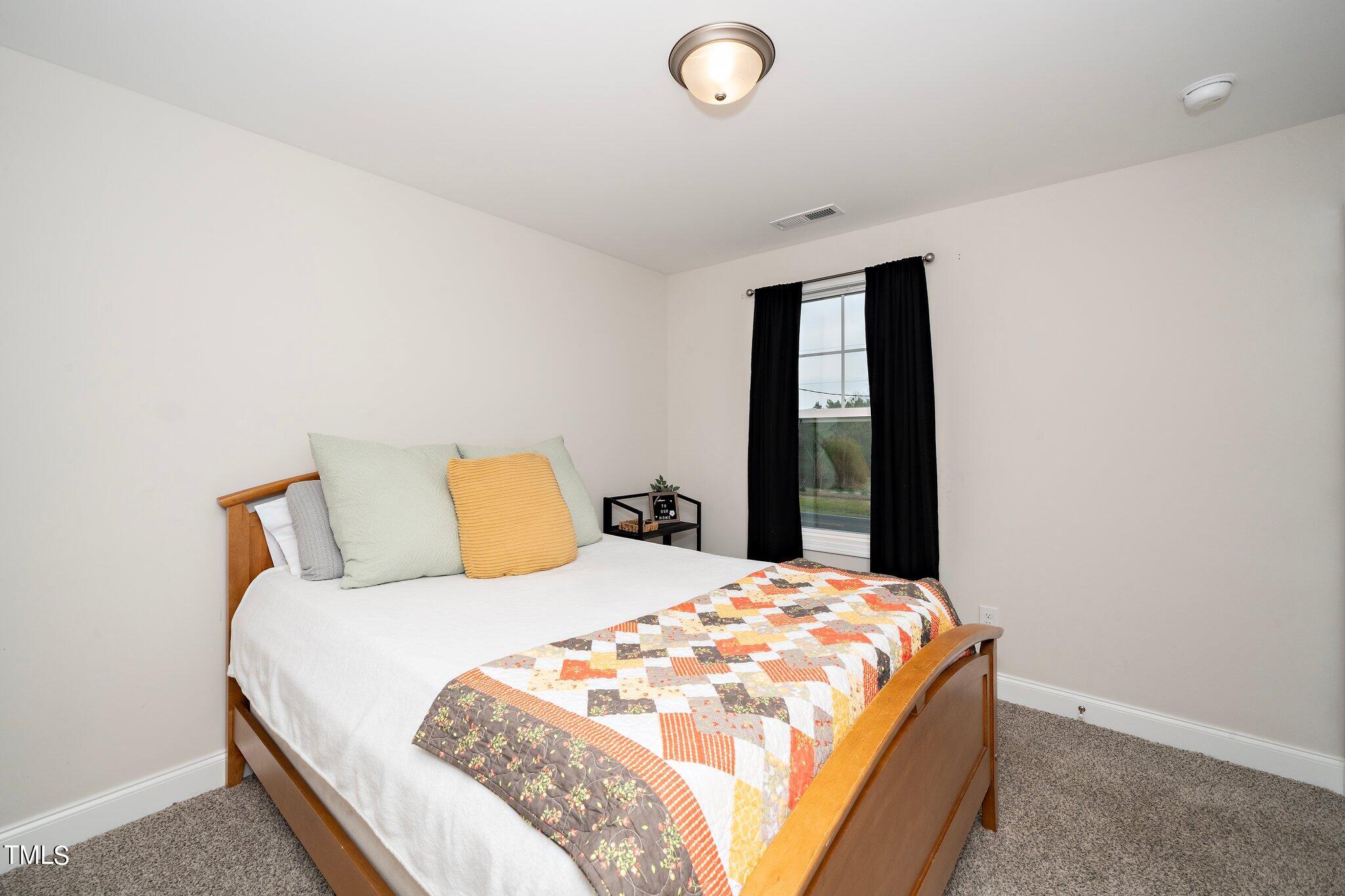 5944 Rosser Pittman Road Sanford, NC 27332 - Photo 11 of 13 a bed sitting in a bedroom next to a window