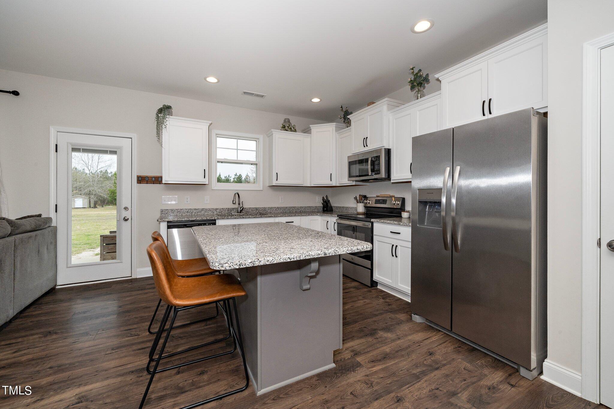 5944 Rosser Pittman Road Sanford, NC 27332 - Photo 3 of 13 a kitchen with stainless steel appliances granite countertop a kitchen island a stove a refrigerator a sink a dining table and chairs
