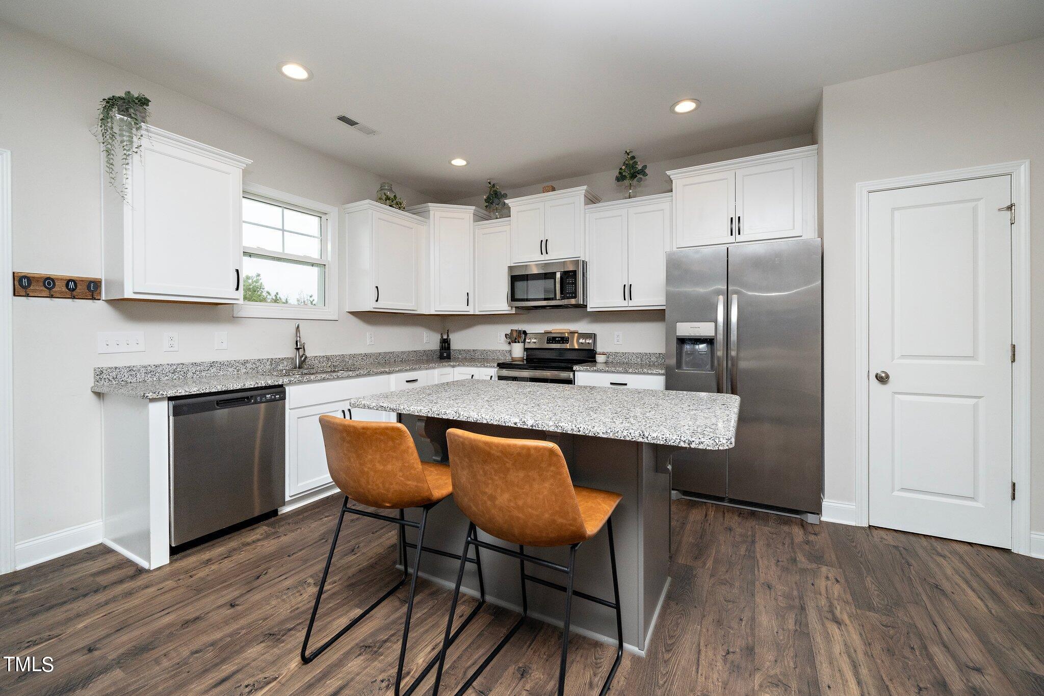 5944 Rosser Pittman Road Sanford, NC 27332 - Photo 4 of 13 a kitchen with stainless steel appliances granite countertop a table chairs sink refrigerator and microwave