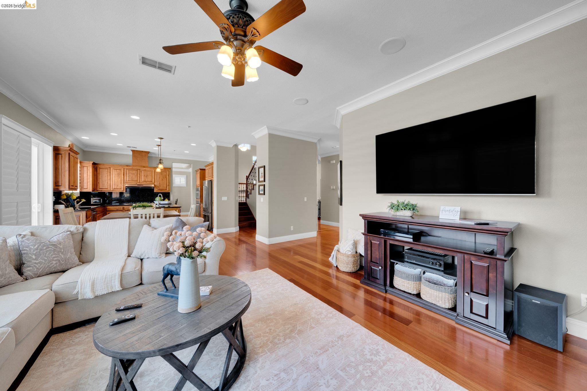 2513 Winged Foot Road Brentwood, CA 94513 - Photo 13 of 45 Open-concept living space featuring wood-finish flooring, recessed lighting, crown molding, a ceiling fan, and a kitchen with wood cabinetry