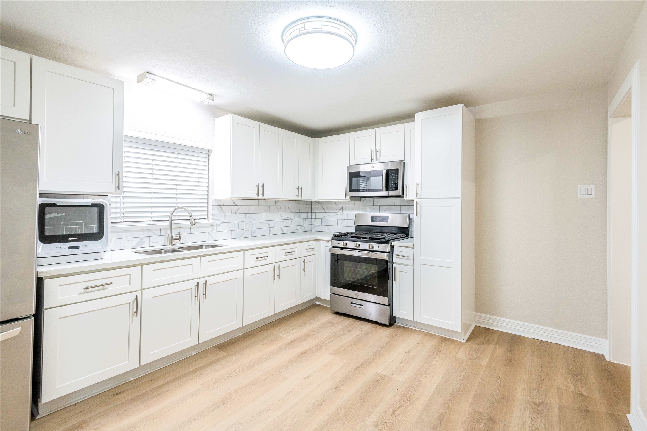 a kitchen with granite countertop a stove a sink and a microwave