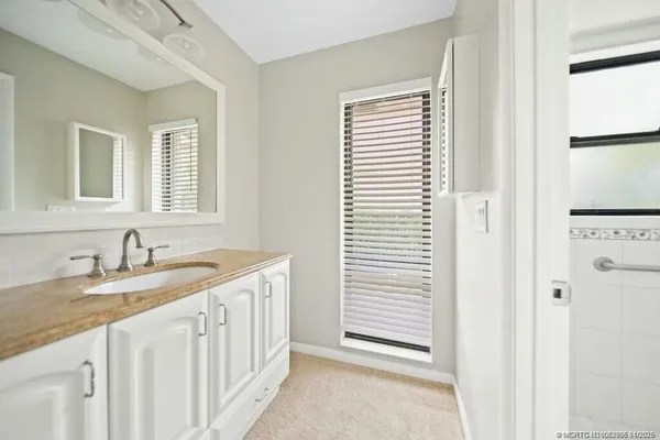 a bathroom with a granite countertop sink and a window