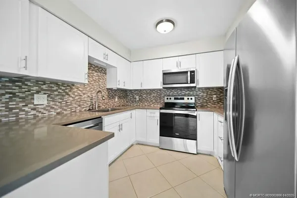 a kitchen with granite countertop a refrigerator and a stove top oven