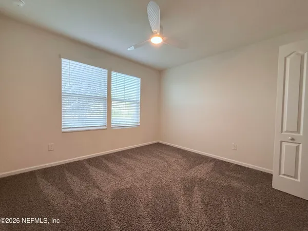 an empty room with windows and fan