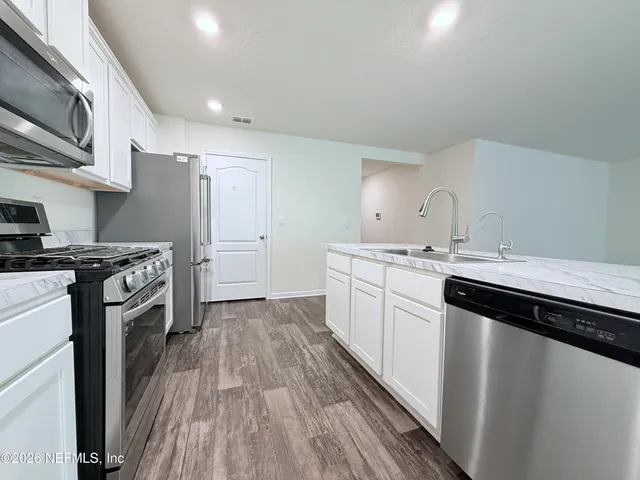 a kitchen with a sink cabinets stainless steel appliances and a window