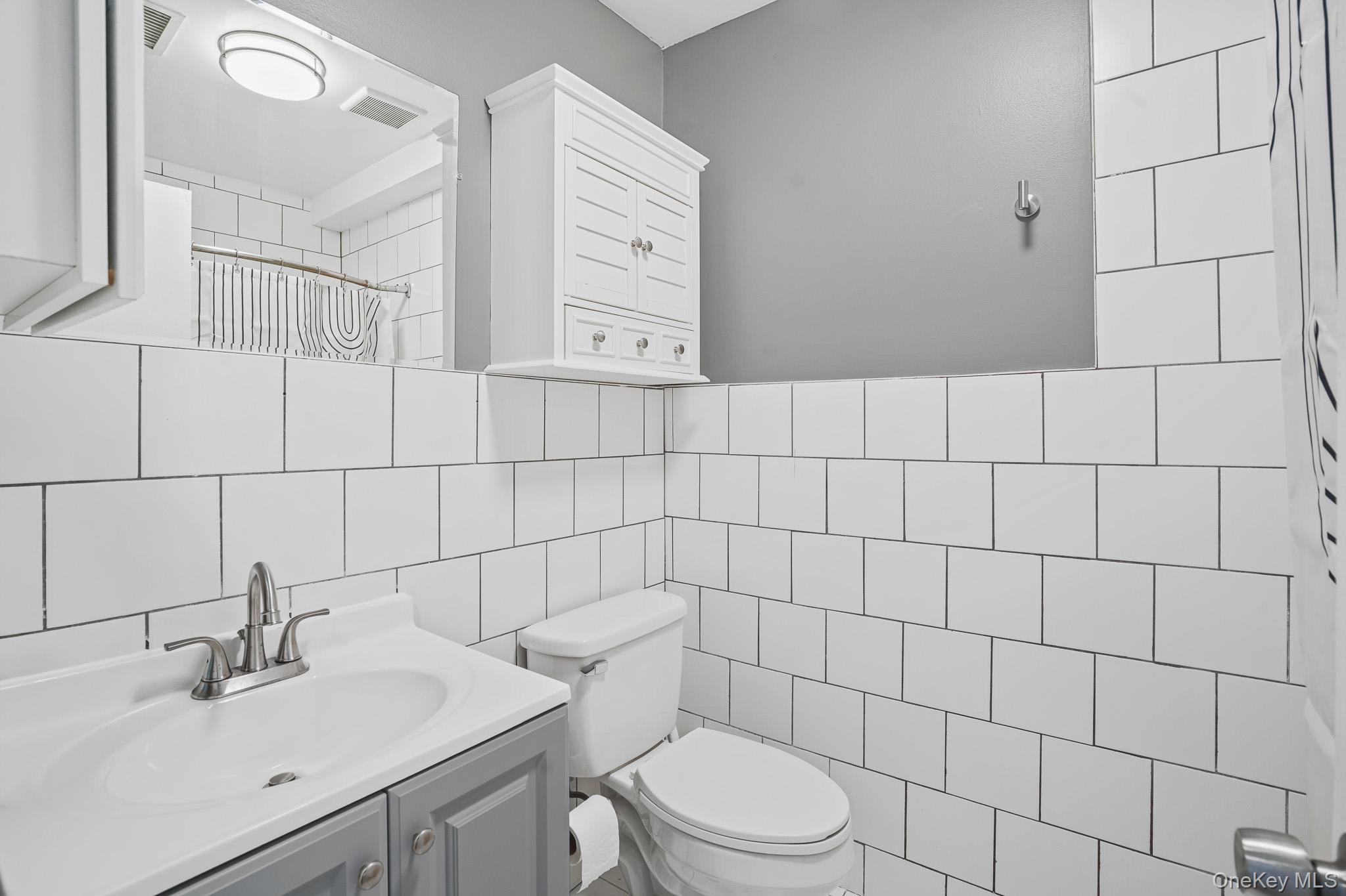26 Cooper Road, Unit 411 Poughkeepsie, NY 12603 - Photo 15 of 17 Bathroom with curtained shower, vanity, and tile walls