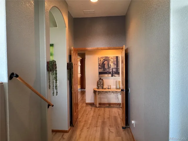 a view of a hallway with wooden floor and furniture