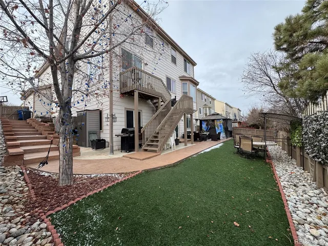 a view of a white house next to a yard with big trees