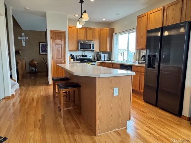 a kitchen with stainless steel appliances granite countertop a refrigerator a stove top oven a sink dishwasher and wooden floor