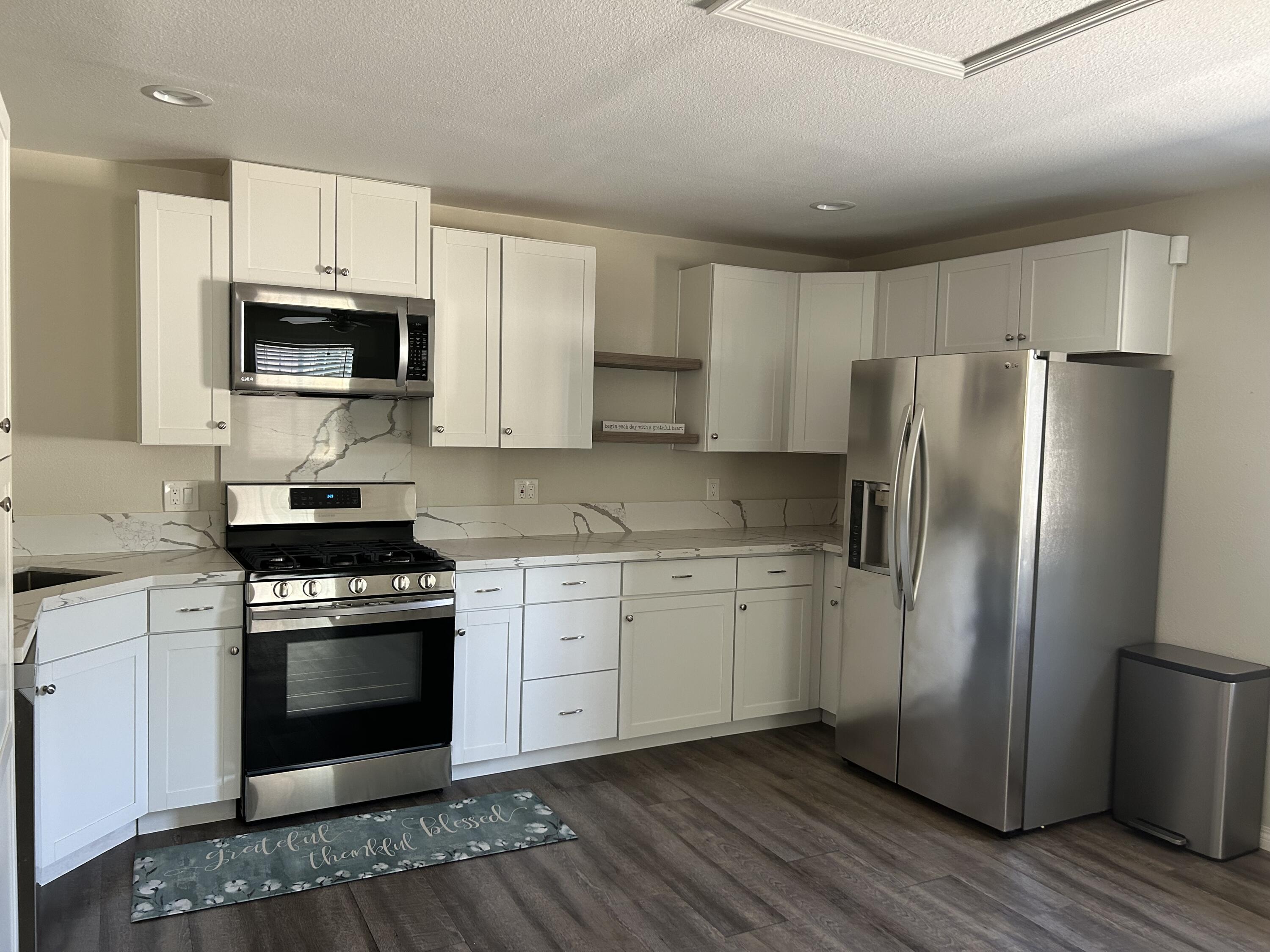 3344 West Ave L Lancaster, CA 93536 - Photo 3 of 9 a kitchen with stainless steel appliances granite countertop a stove a refrigerator and a microwave