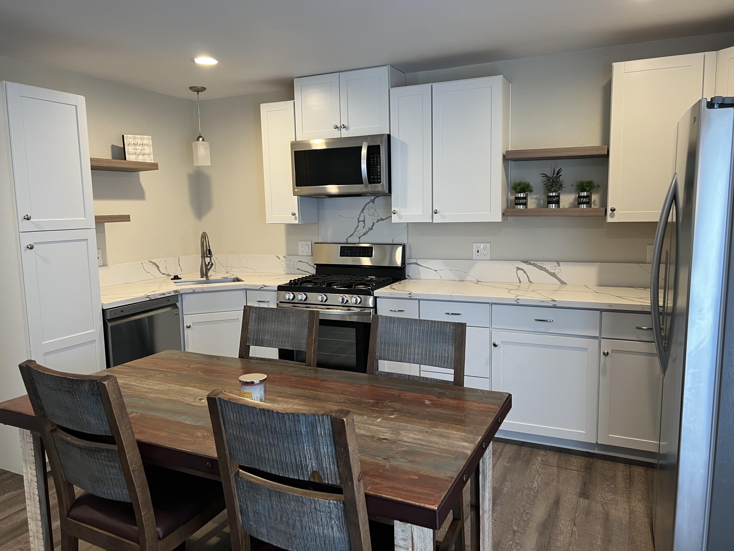 3344 West Ave L Lancaster, CA 93536 - Photo 4 of 9 a kitchen with a table chairs microwave and cabinets