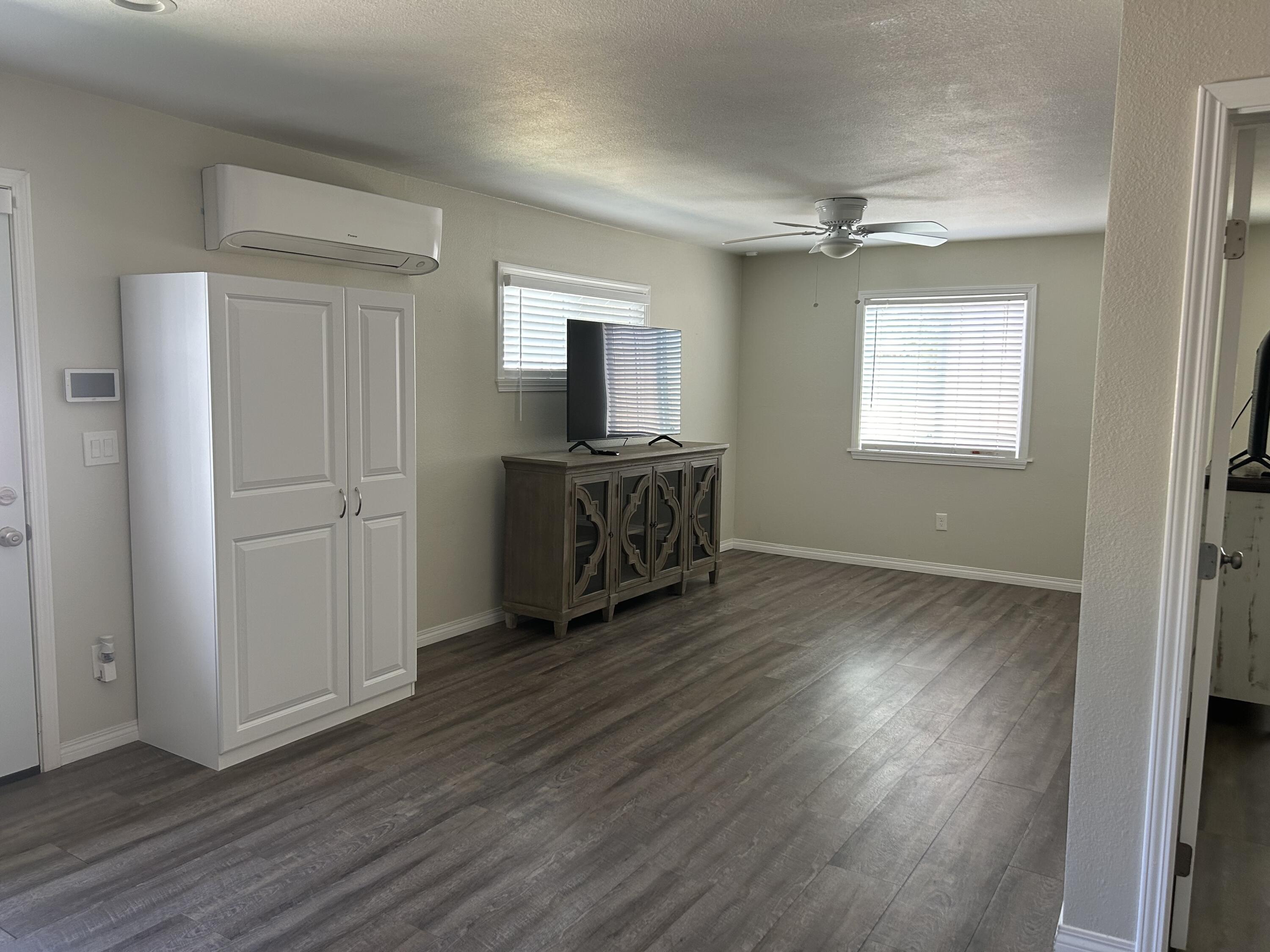 3344 West Ave L Lancaster, CA 93536 - Photo 5 of 9 an empty room with wooden floor cabinet and windows