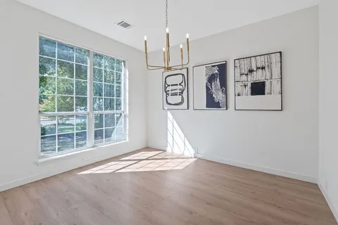 an empty room with wooden floor cabinet and windows