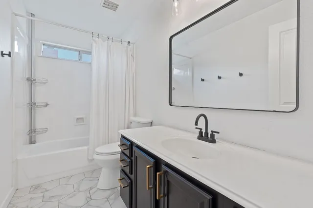 a bathroom with a sink a toilet a mirror and shower