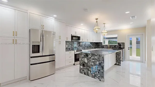 a kitchen with kitchen island granite countertop a sink a counter top space appliances and cabinets