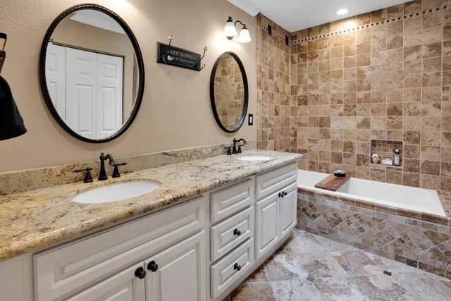 a bathroom with a granite countertop double vanity sink and a mirror