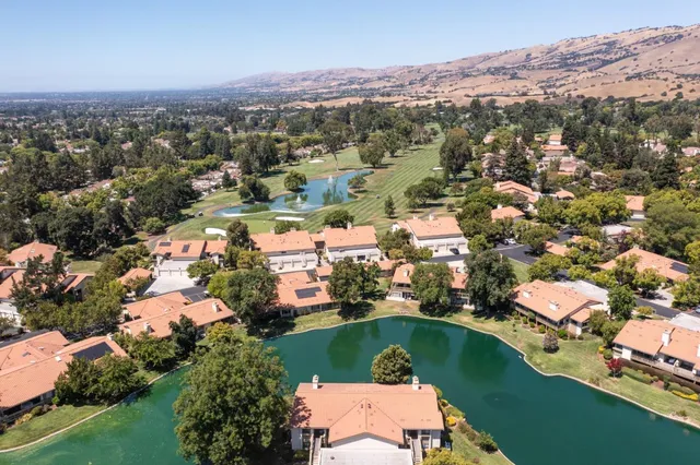 an aerial view of a city with lots of residential buildings ocean and mountain view in back