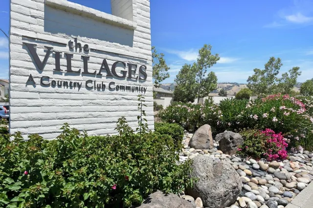 a view of a sign board with buildings in the background