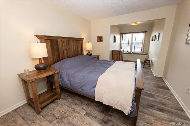 a spacious bedroom with a bed and wooden floor