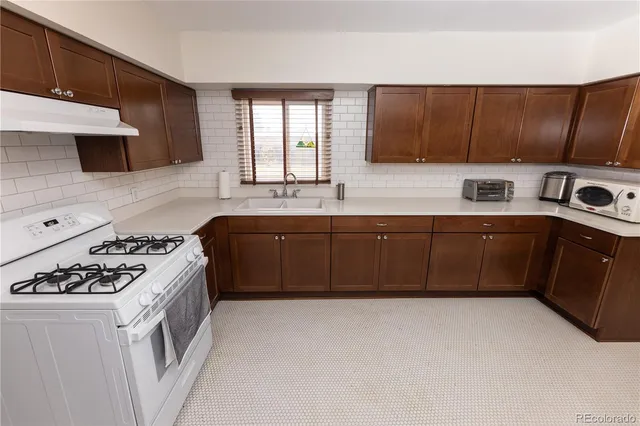 a kitchen with stainless steel appliances a sink a stove a microwave and wooden cabinets