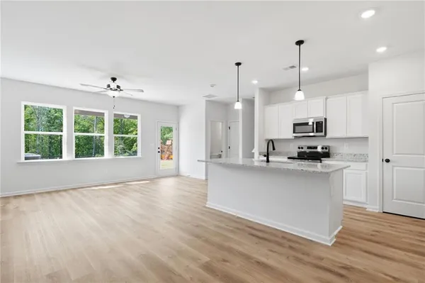 a open kitchen with stainless steel appliances granite countertop a stove a sink a center island a stove and a wooden floors