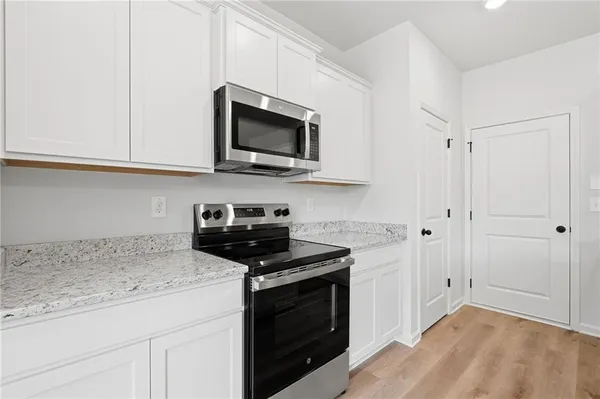 a kitchen with stainless steel appliances granite countertop white cabinets and a stove