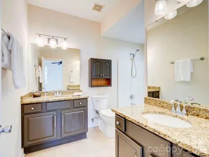 a bathroom with a granite countertop double vanity sink and mirror