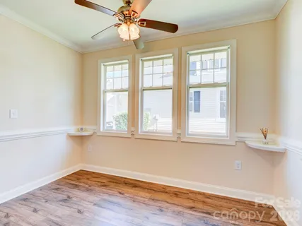 an empty room with wooden floor fan and windows