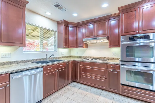 a kitchen with stainless steel appliances granite countertop wooden cabinets and a stove top oven