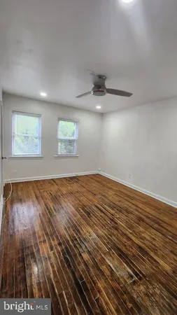 an empty room with wooden floor chandelier fan and windows
