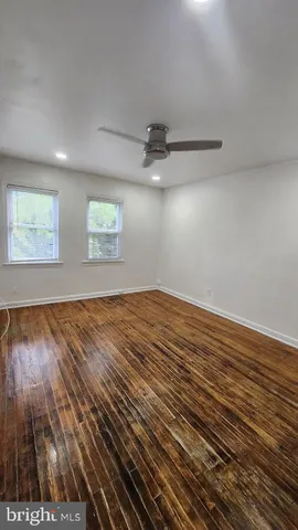an empty room with wooden floor chandelier fan and windows