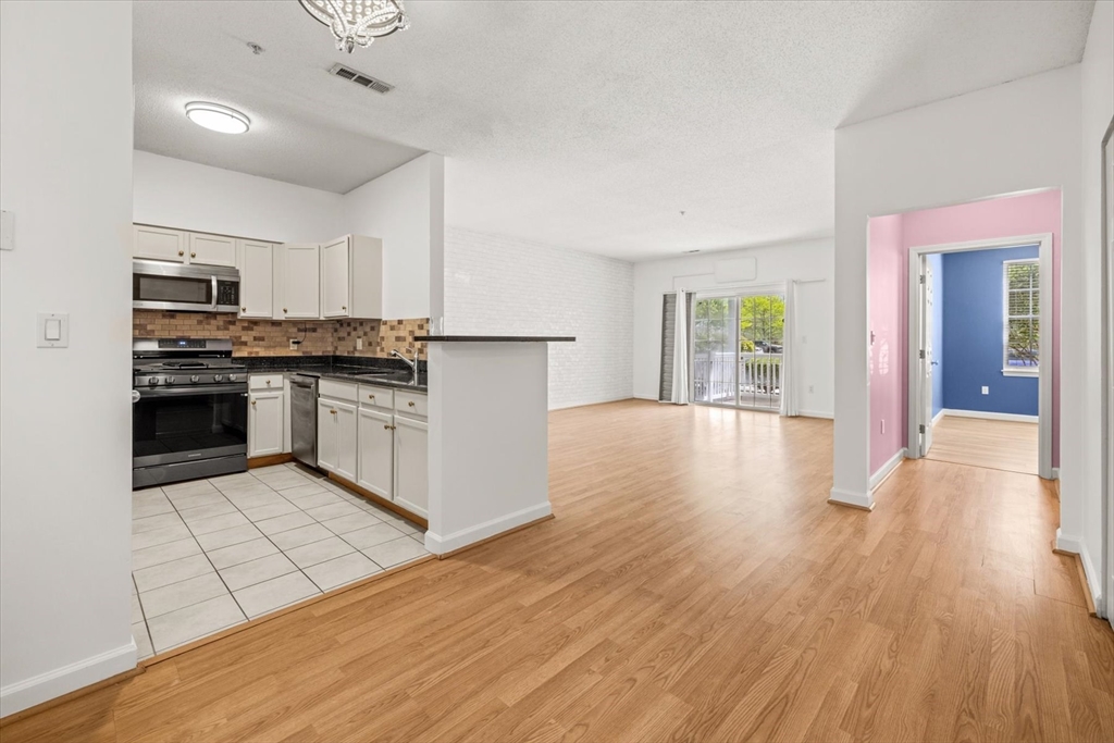 21 Hampshire Road, Unit 101 Methuen, MA 01844 - Photo 6 of 18 a kitchen with stainless steel appliances granite countertop a stove top oven a sink dishwasher and a refrigerator with wooden floor