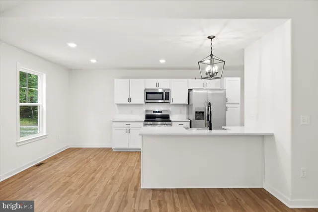 a kitchen with stainless steel appliances granite countertop a refrigerator a stove oven a sink dishwasher and white cabinets with wooden floor