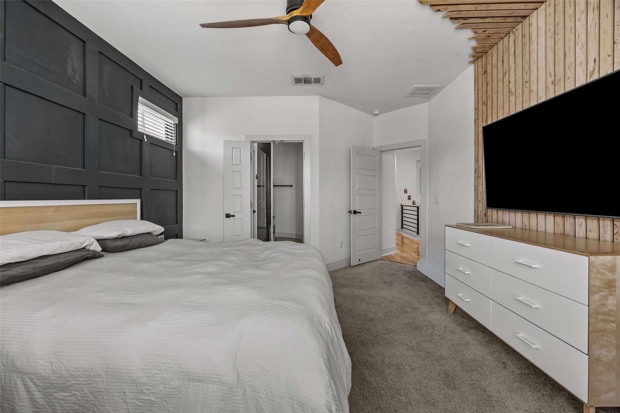 1408 Homespun Road Austin, TX 78745 - Photo 14 of 20 A naturally illuminated bedroom with a captivating paneled wall and a warm wood-slatted feature wall.