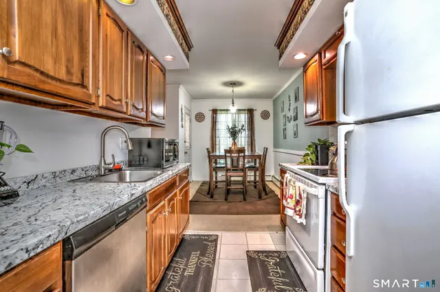 a kitchen with granite countertop a stove a sink and a refrigerator