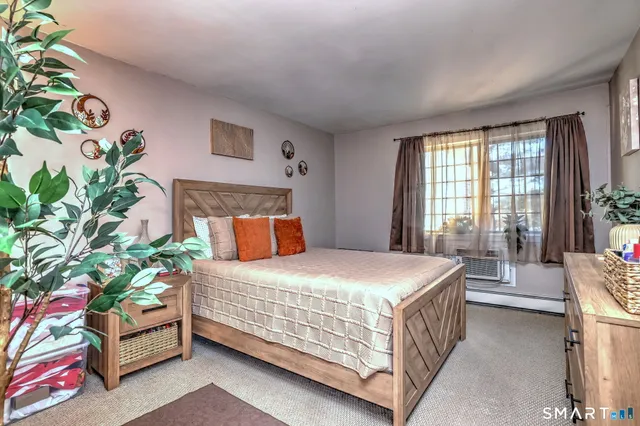 a bedroom with a bed table flowerpot and window